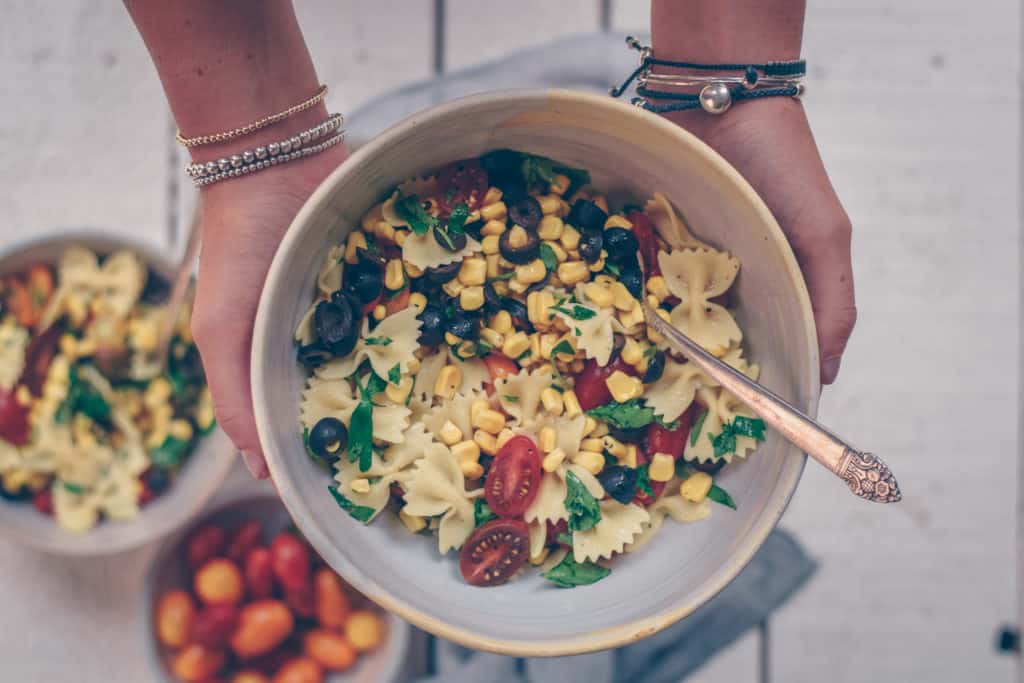 Bowtie Pasta Salad in a bowl with hands holding it