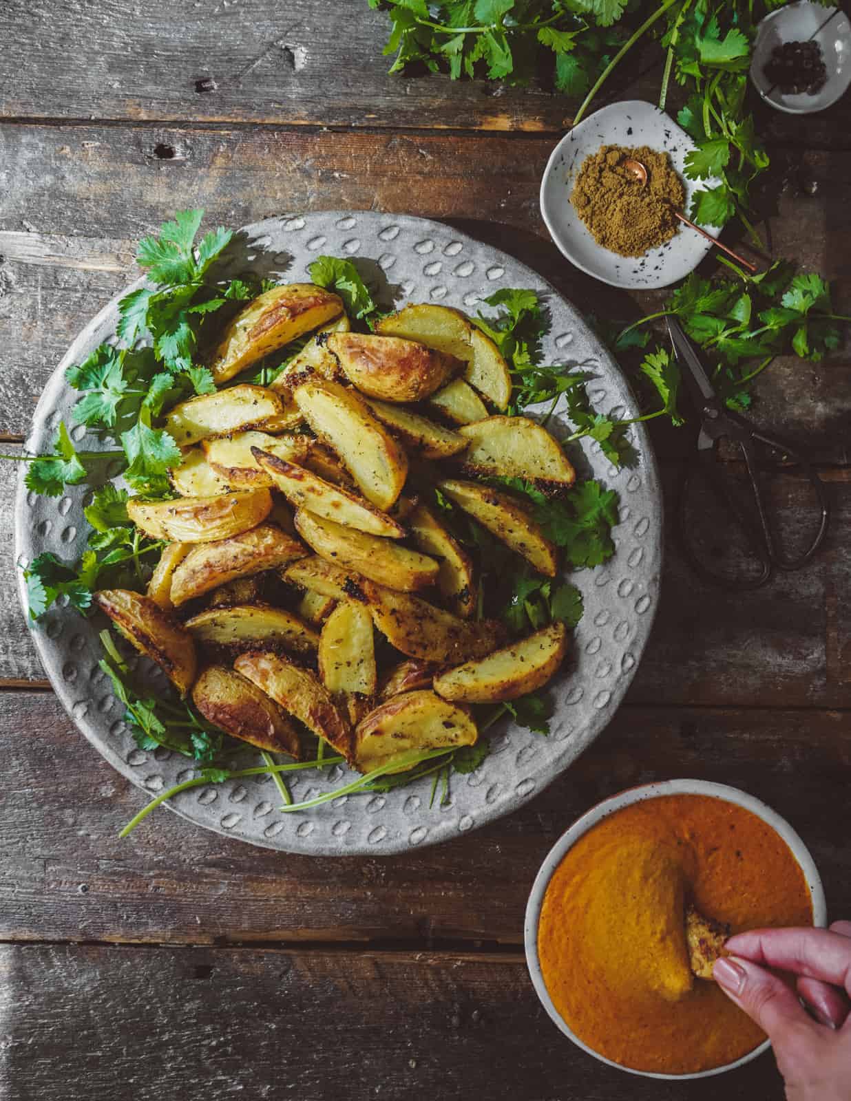 White dish with curry chips on a bed of herbs.