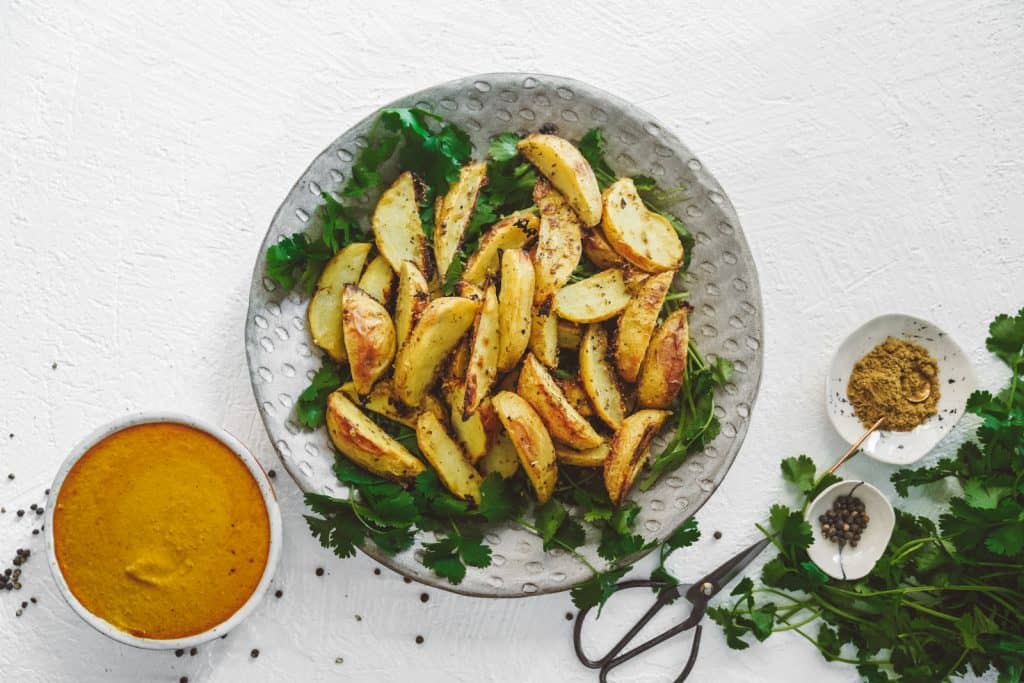 Serving dish with curry chips. Freshly baked potatoes next to curry sauce.