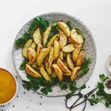 Serving dish with curry chips. Freshly baked potatoes next to curry sauce.