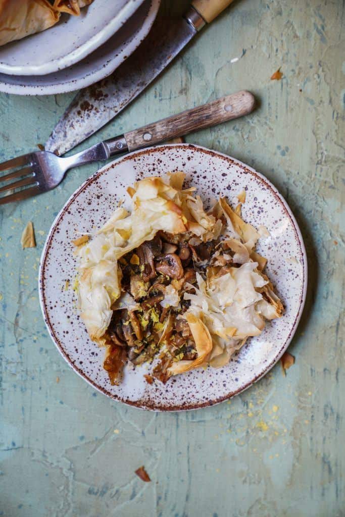 vegan filo pastry bites with mushrooms exploding out of them on plate.