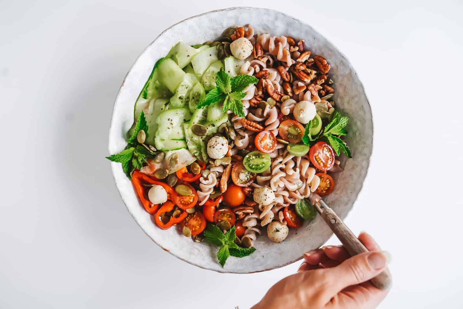 Easy Pumpkin Seed Pasta Salad in a bowl on a counter with a spoon serving it.