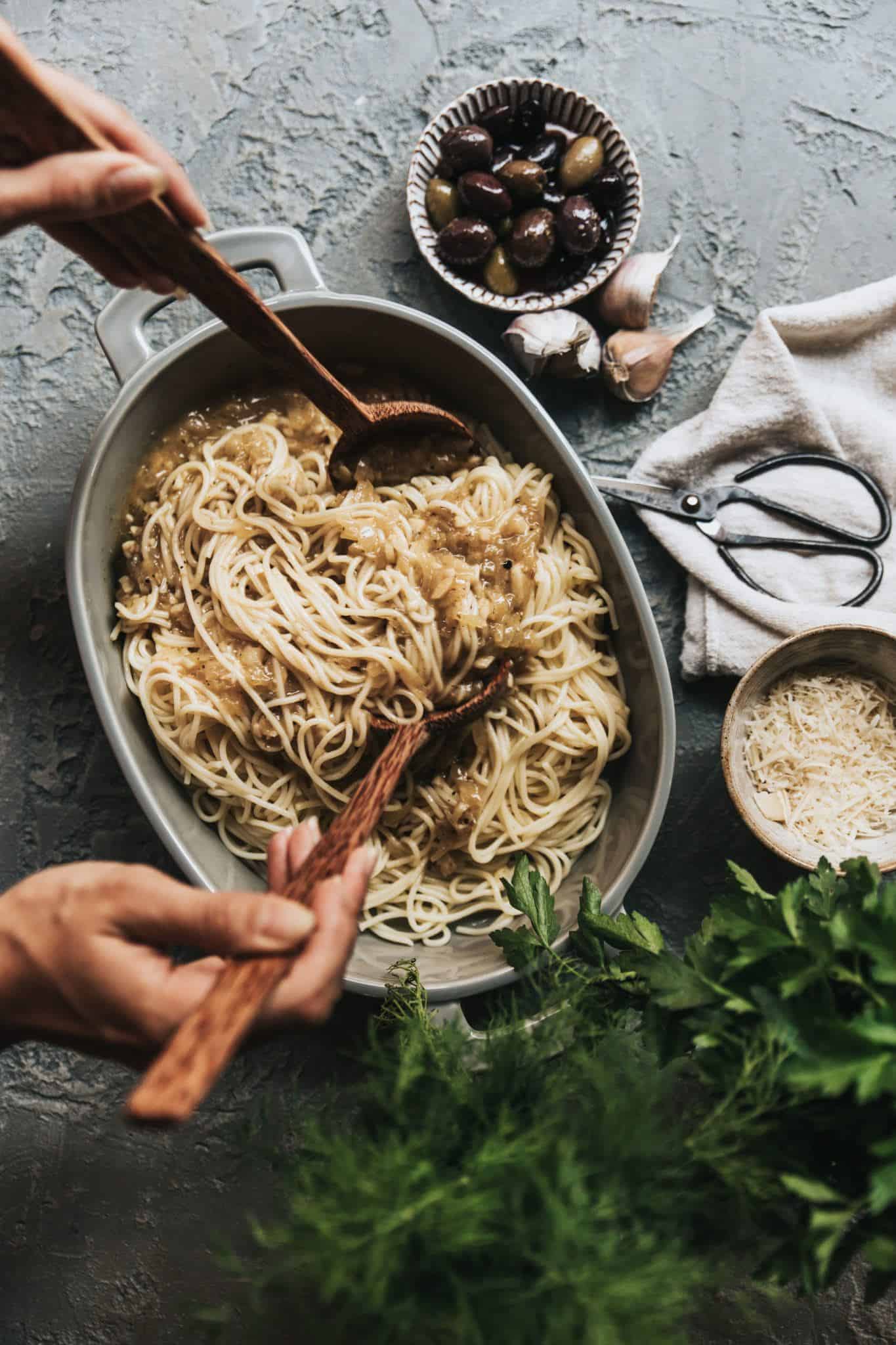 Mixing all the flavours together for this easy vegan truffle pasta in a large serving bowl on the counter.