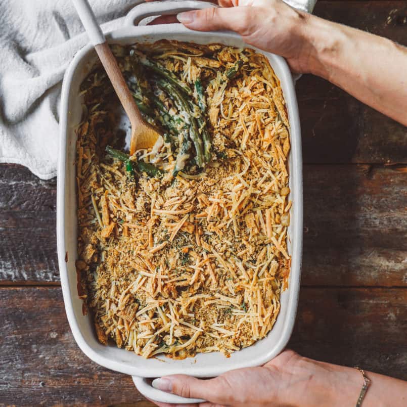 Hands holding a casserole dish of green bean casserole