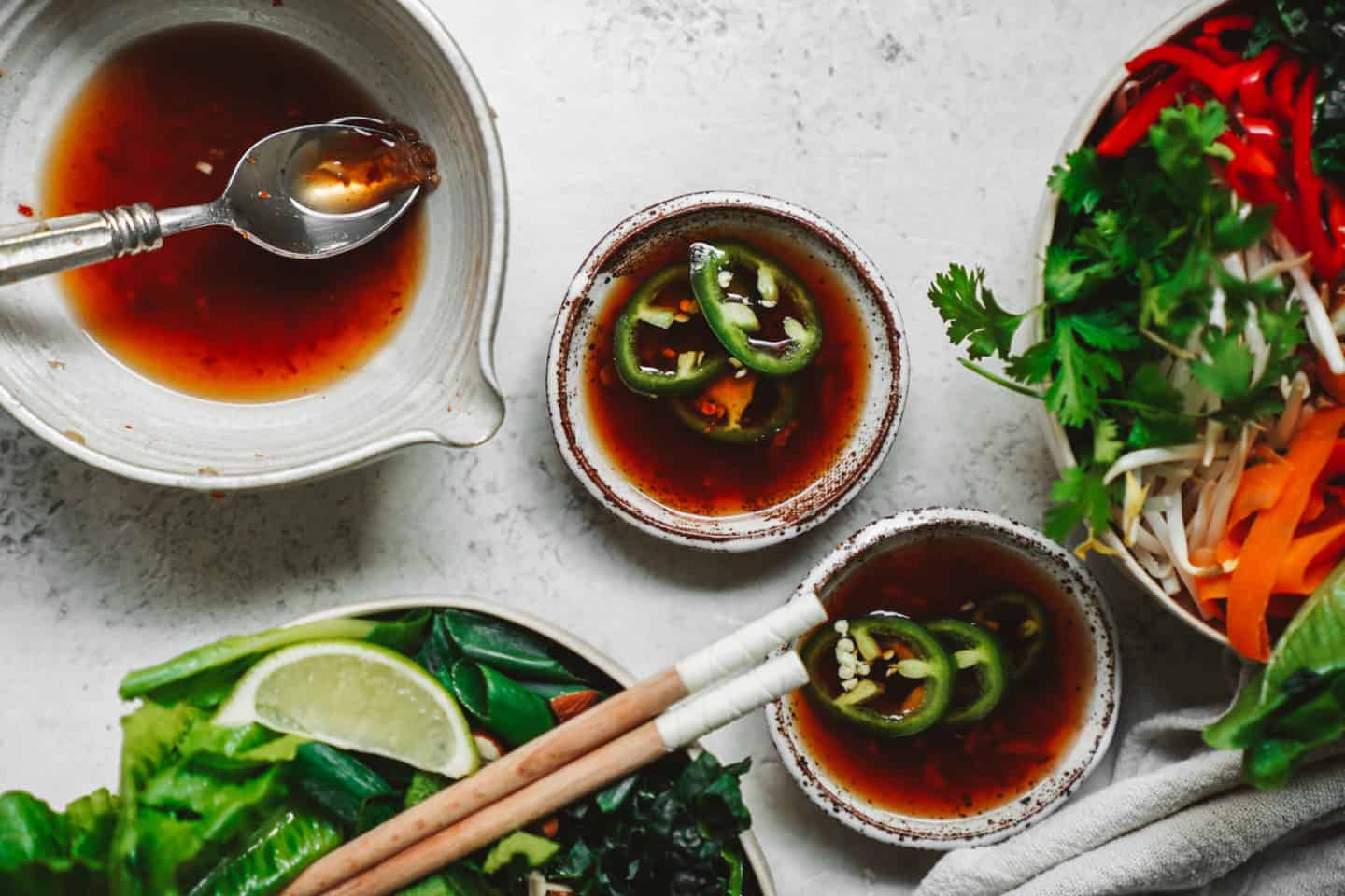 Little bowls of Vegan Fish Sauce next to ingredients for spring roll bowl.