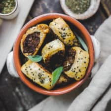 Bowl of vegan sausage rolls surrounded by spices.