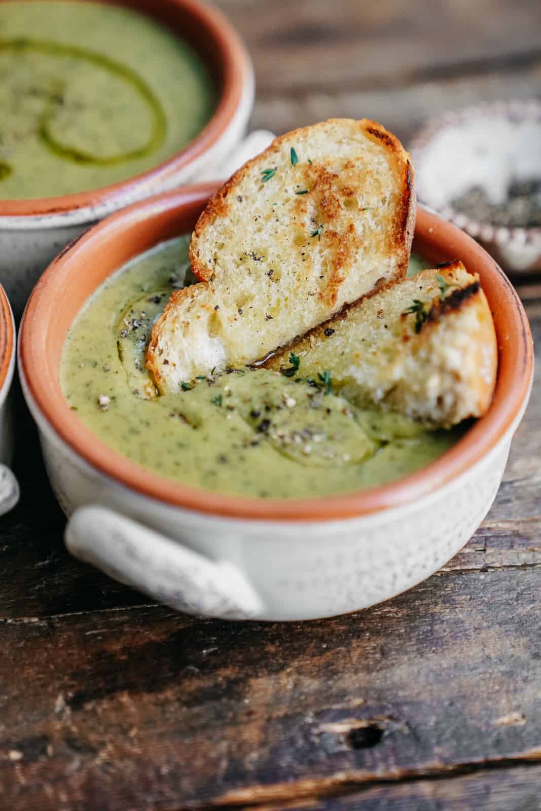 Close-up of Vegan Broccoli Cheese Soup ready to eat with 2 slices of toasted baguette. 