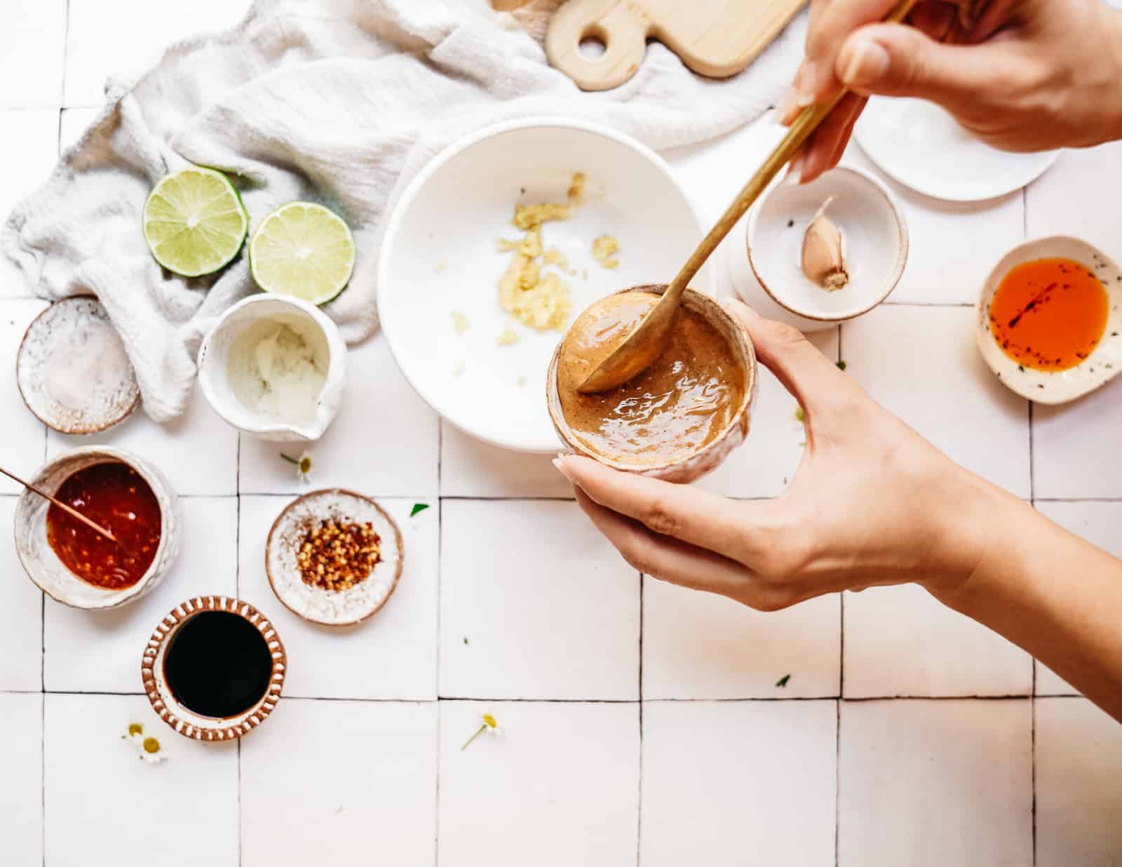 Person showing you how to make peanut sauce in a bowl on a white countertop