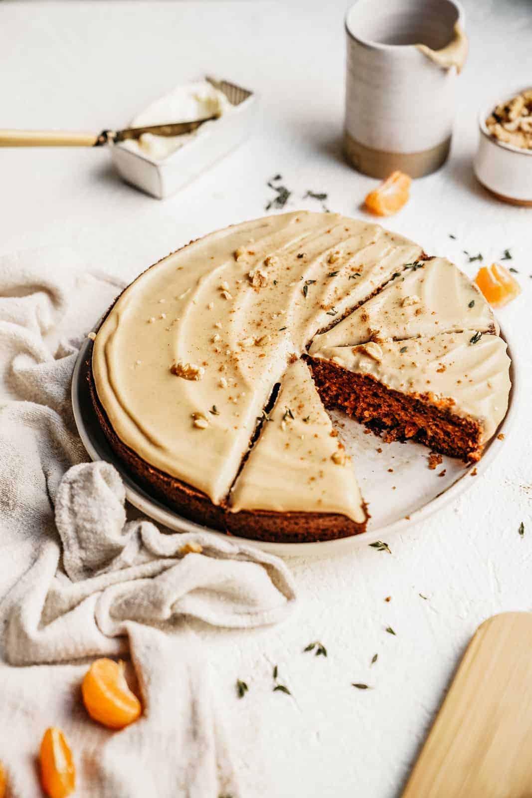 A vegan carrot cake sitting on counter, sliced and ready to eat.