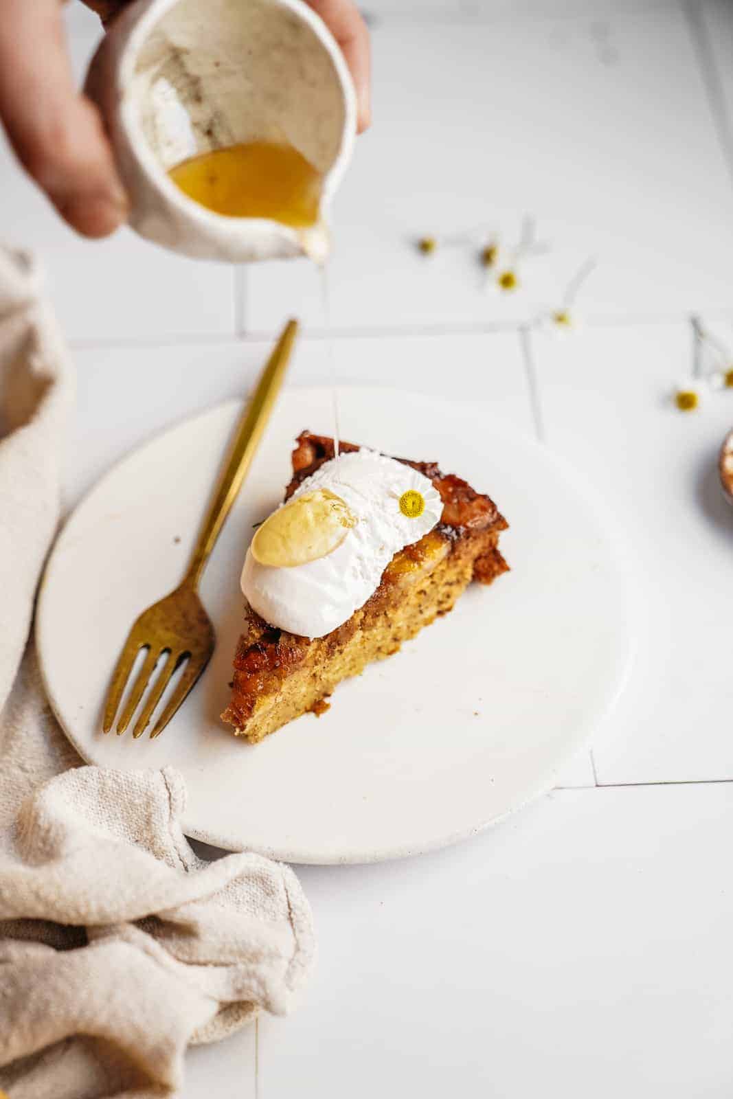 Slice of banana bread cake on plate with honey being drizzled on top