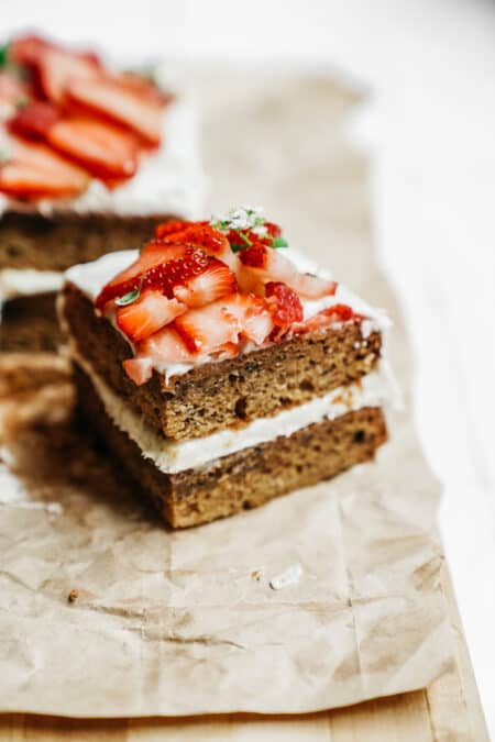 Slice of delicious Honey Cake made with BeeMaid Honey. Topped with fresh strawberries sitting on parchment paper.