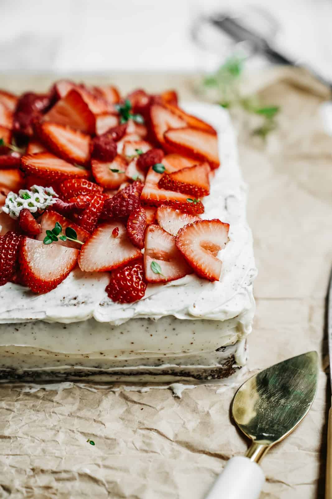 A close-up of the corner of a lovely one-bowl vanilla honey cake with fresh cut strawberries on top, ready to serve.