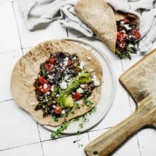 Cutting board next to plant-based vegetable wrap ready to be served for lunch.