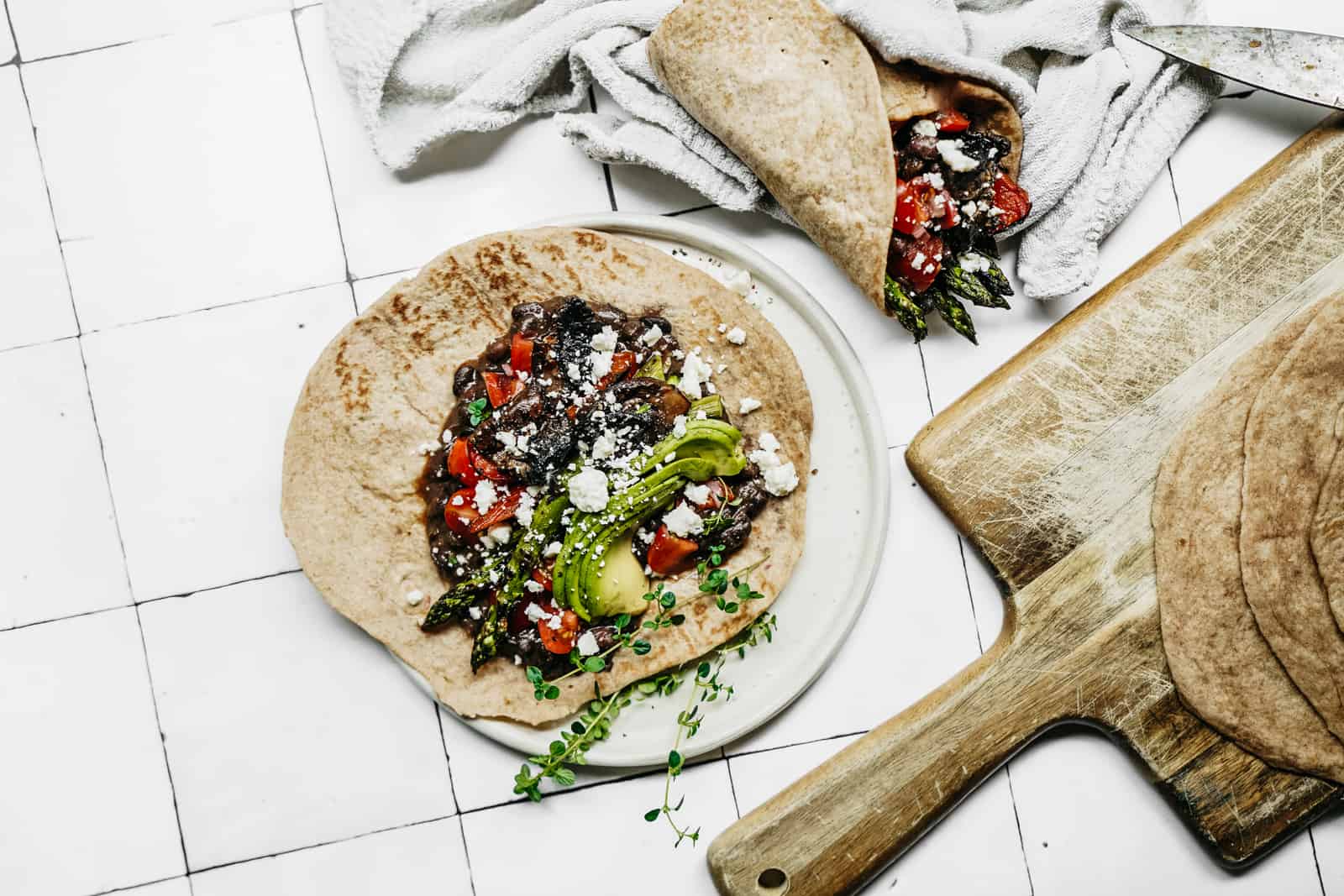 Cutting board next to plant-based vegetable wrap ready to be served for lunch.