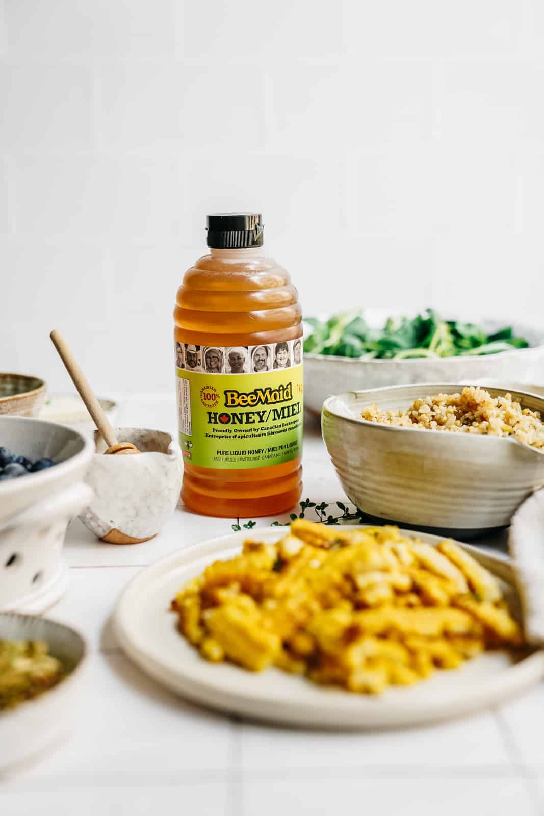 BeeMaid honey sitting on countertop surrounded by ingredients to make a healthy salad.