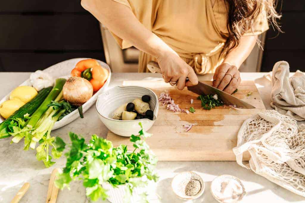 Maria cutting herbs on a cutting board to showcase her interacting with food in her phogoraphy.