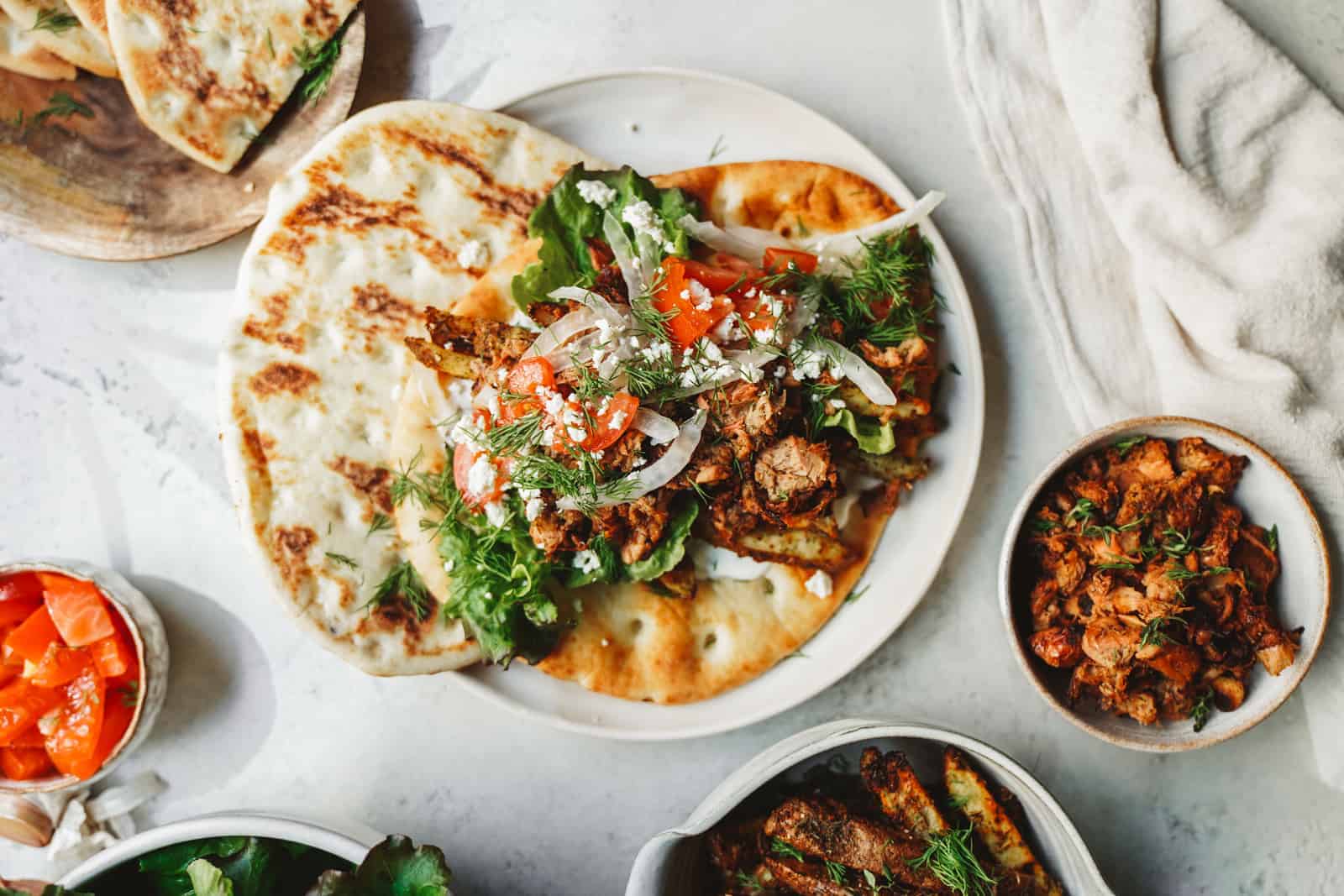 Yummy jackfruit gyros laid out on fresh pita with fresh herbs and tomato toppings. One of the best vegan meals. 