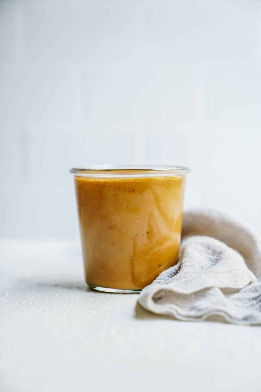 Jar of vegan salad dressing on the white countertop.