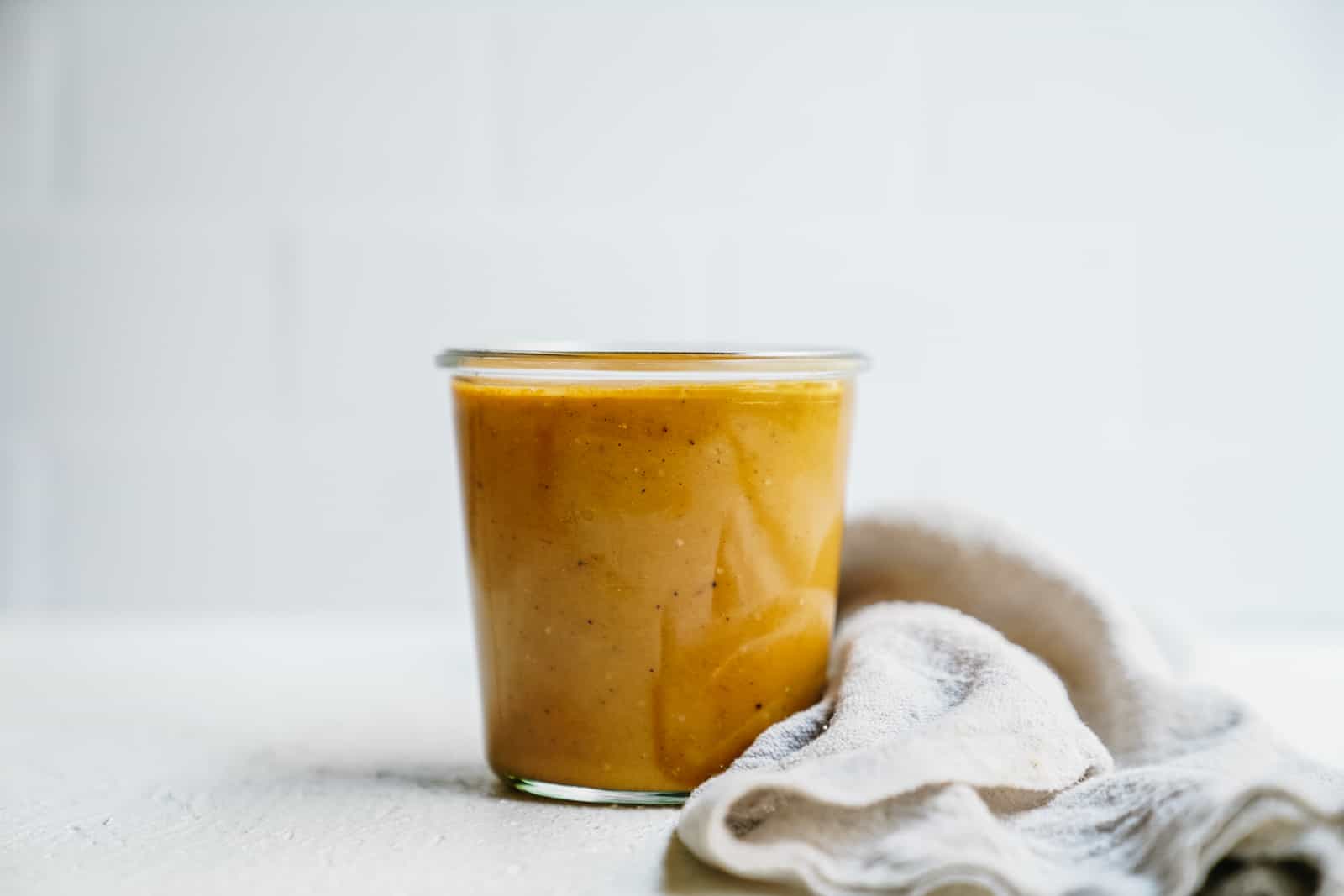 Jar of Tomatillo Dressing on countertop with cloth napkin beside it.