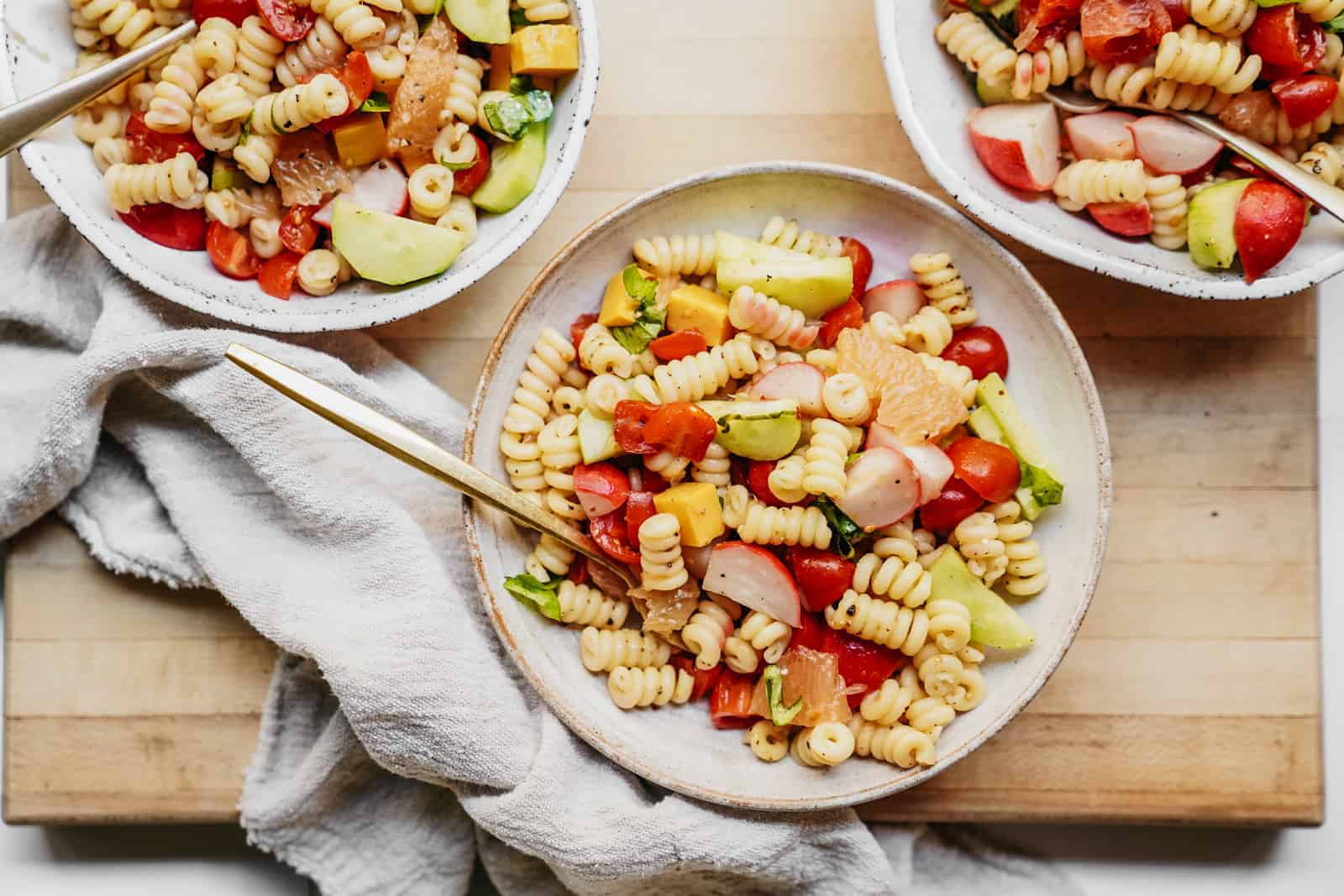 Yummy, colourful bowls of Vegan Pasta Salad sitting on countertop with napkin.