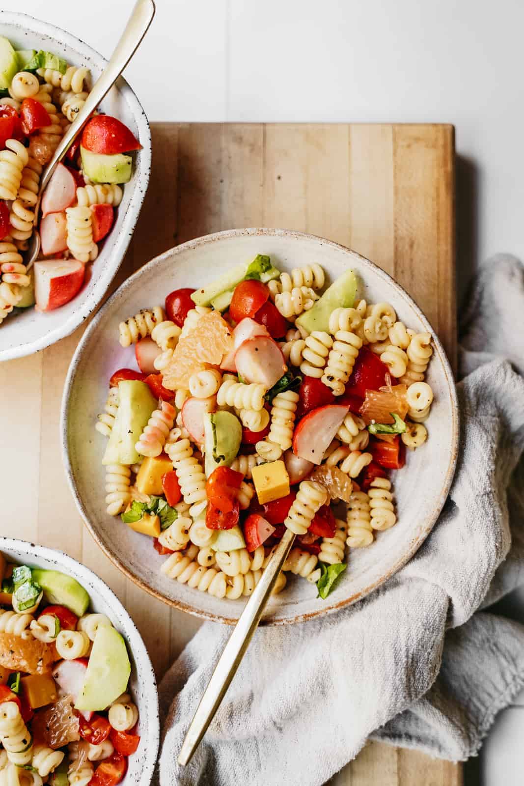 Light and fresh Vegan Pasta Salad sitting on cutting board in bowls ready to be eaten.