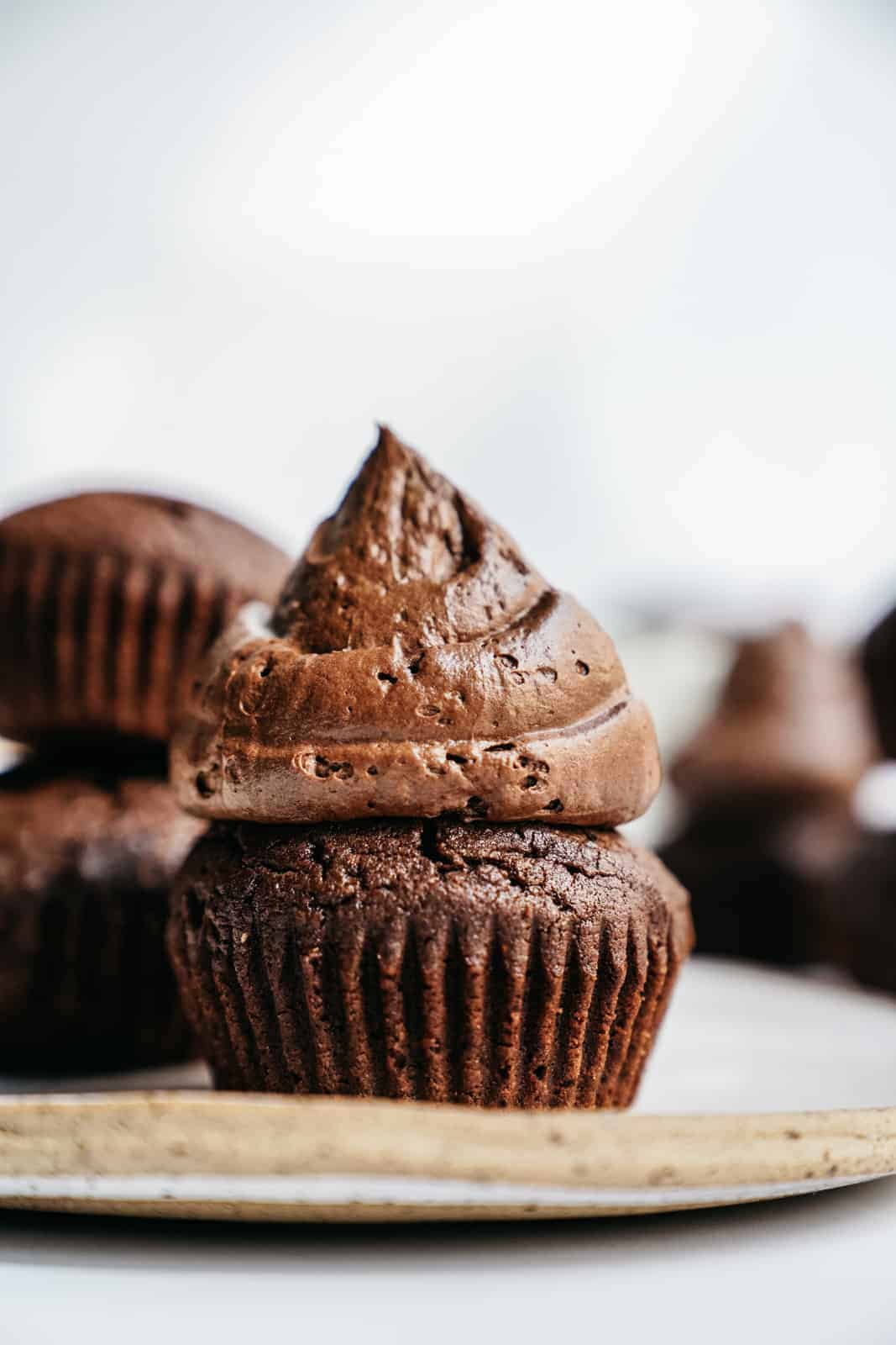 A side angle of a big dollop of creamy vegan icing on top of a brownie muffin.