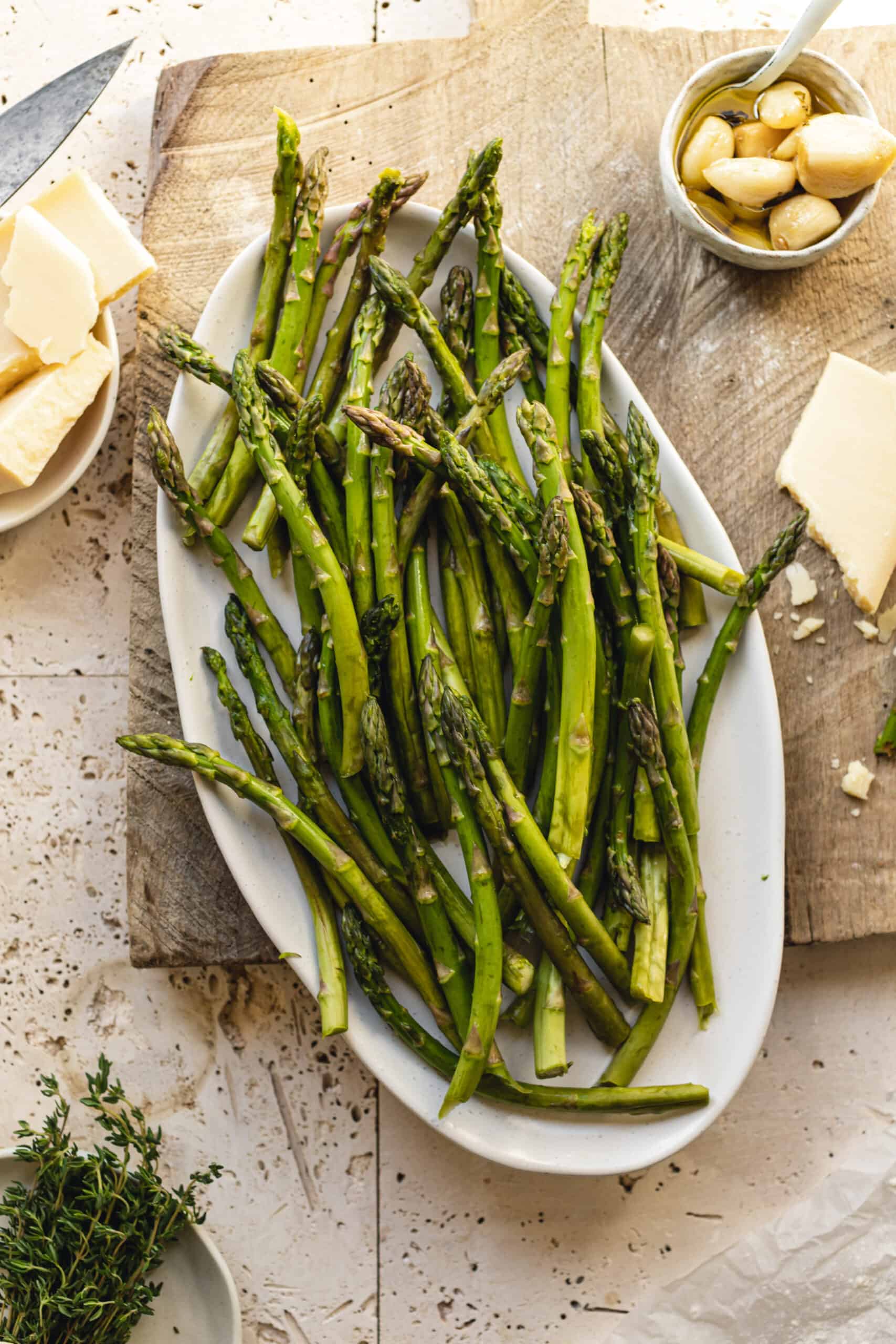 Fresh seasonal asparagus on cutting board beside ingredients for the Asparagus and Cheese Tart.