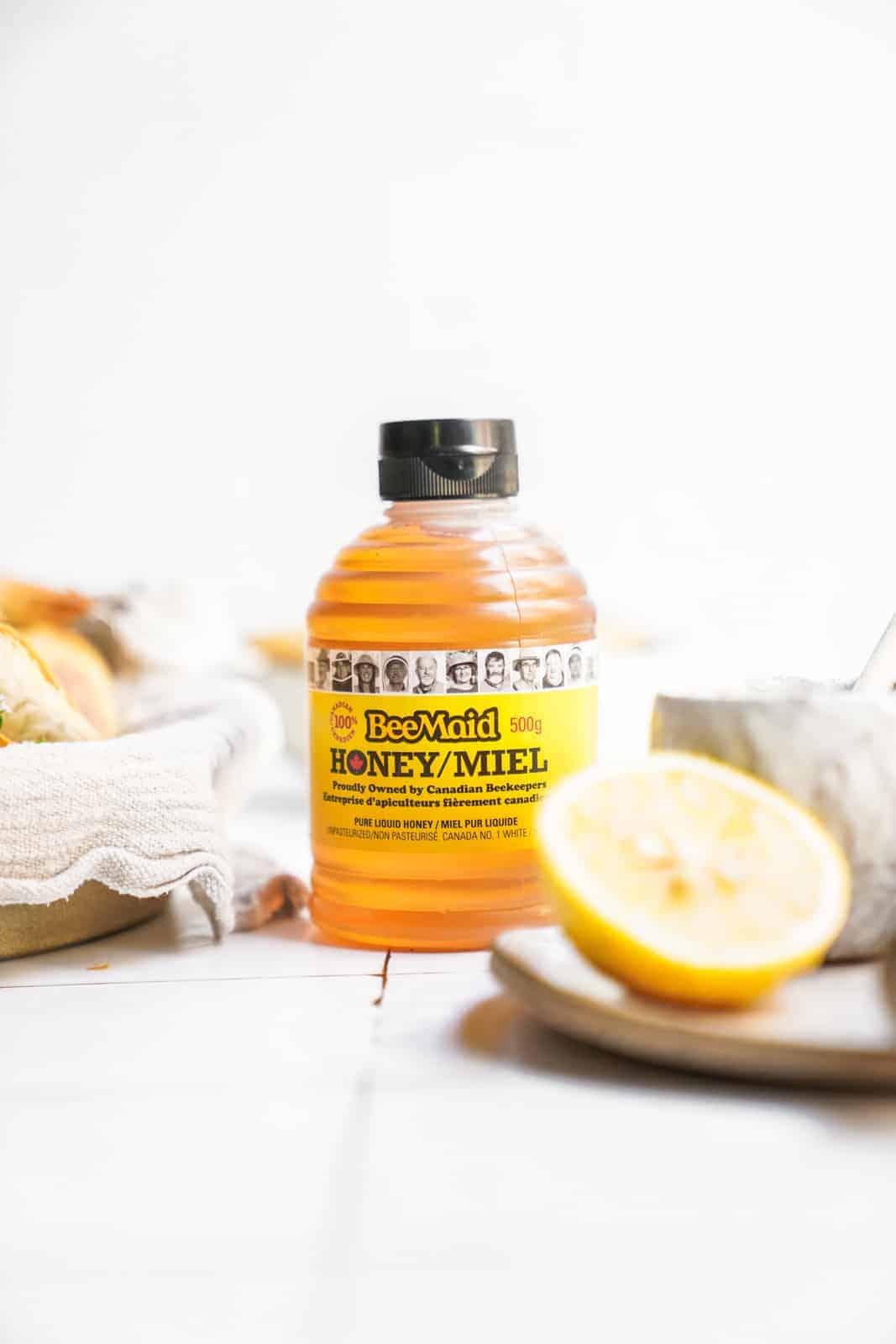 Bottle of honey on countertop surrounded by ingredients.