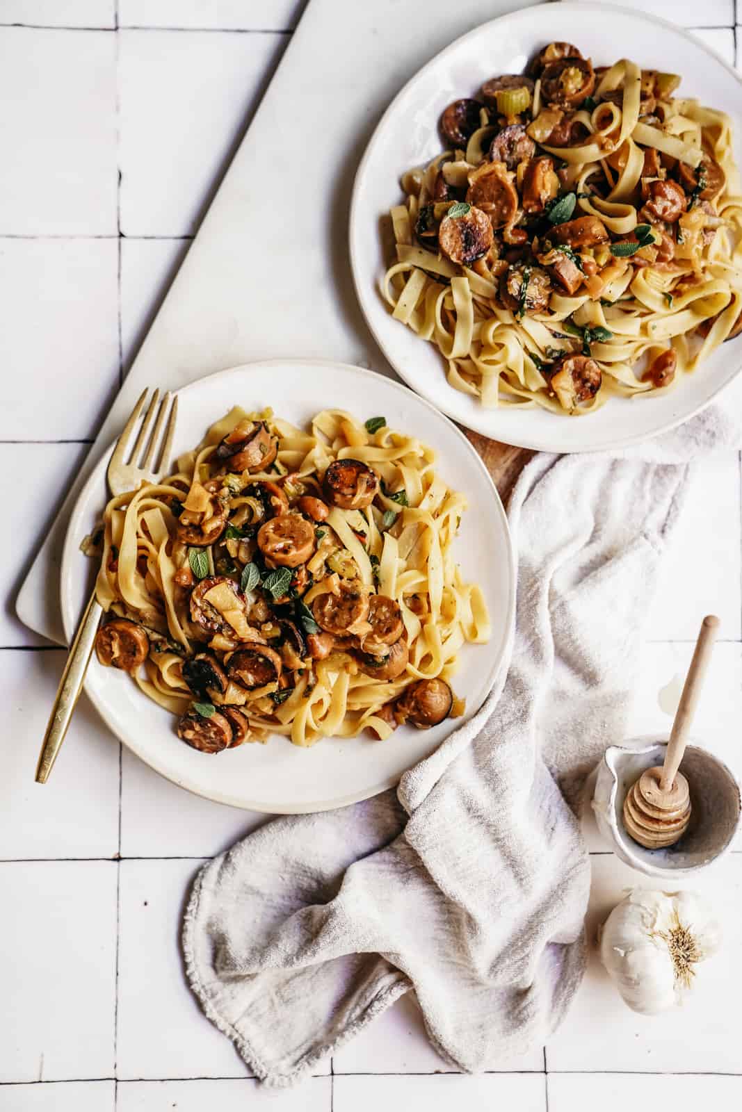 Two plates of Vegan Sausage Pasta on white countertop.