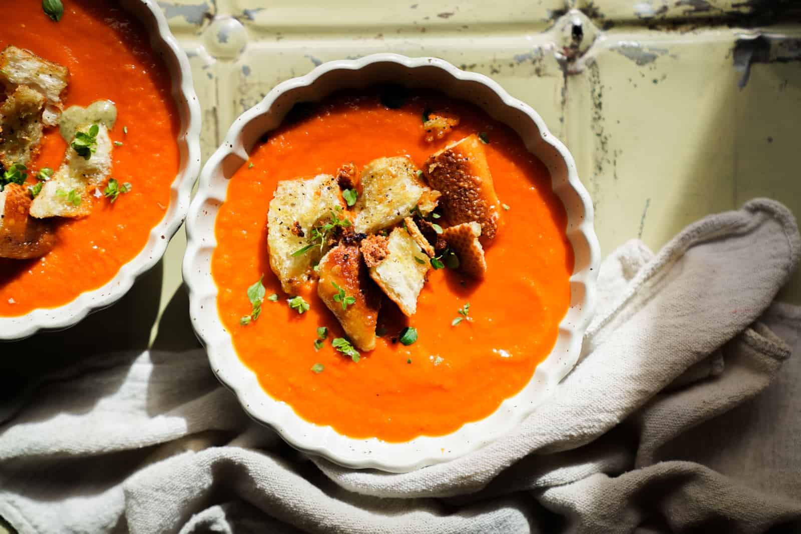 Overhead photo of Roasted Tomato Soup with garlic crotons and basil on top