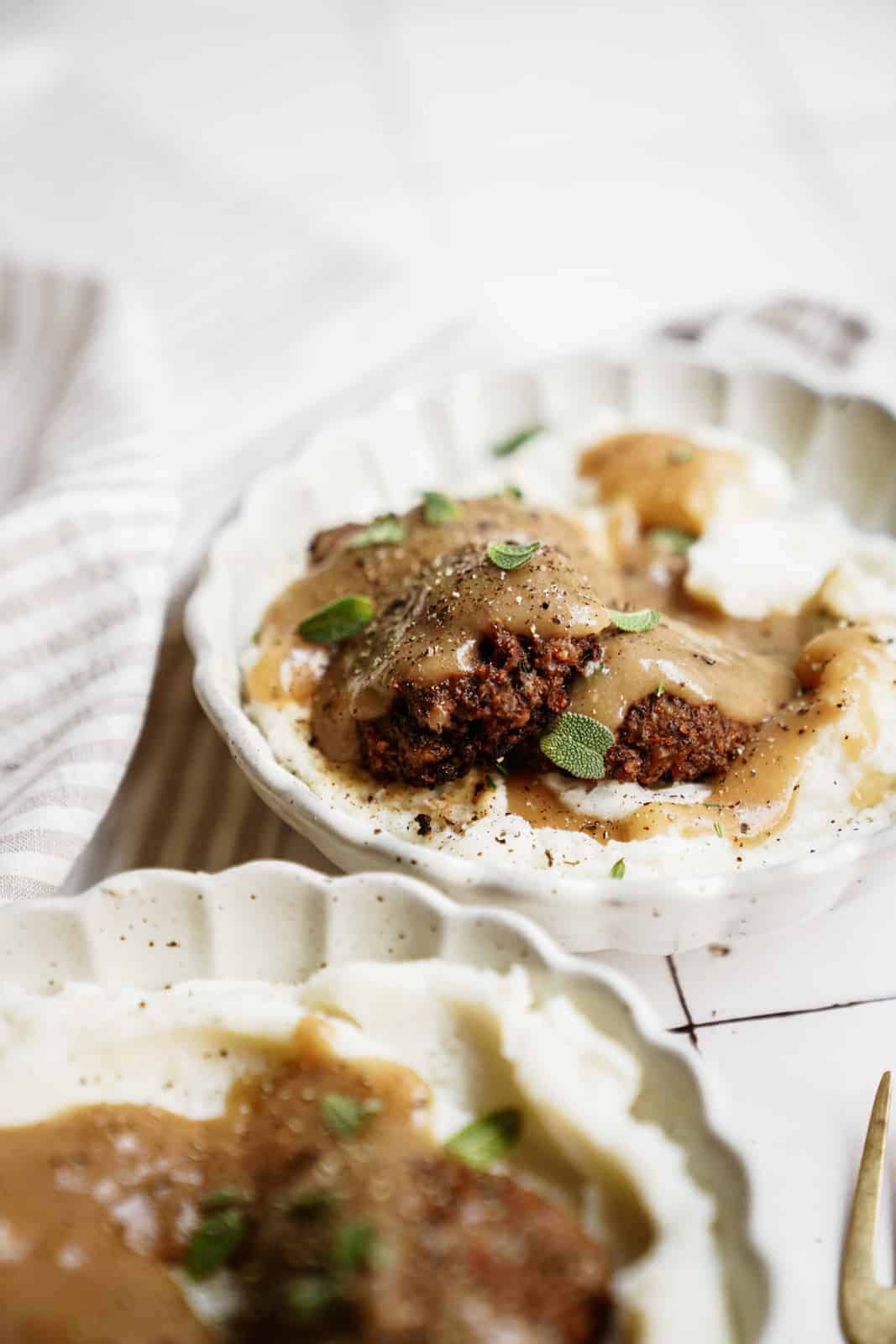 Vegan meatballs with a side of vegan mashed potatoes and gravy on countertop.