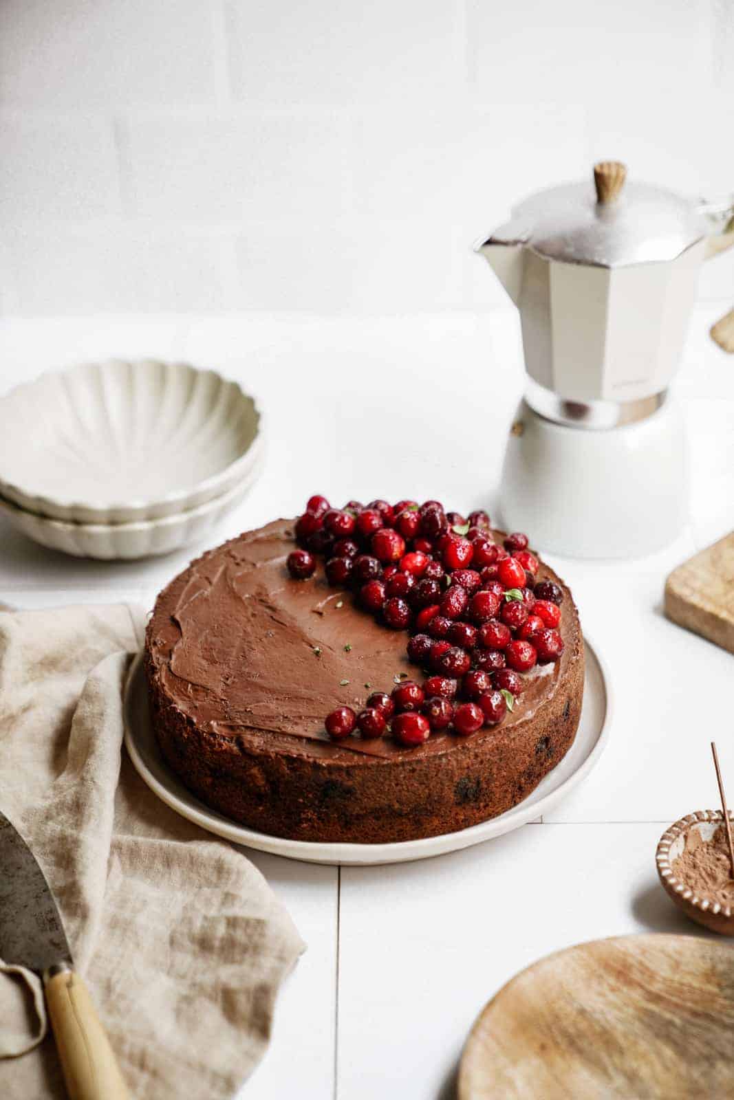 Pecan Coffee Cake on counter with fresh cranberries on top and a slice ready to be served.