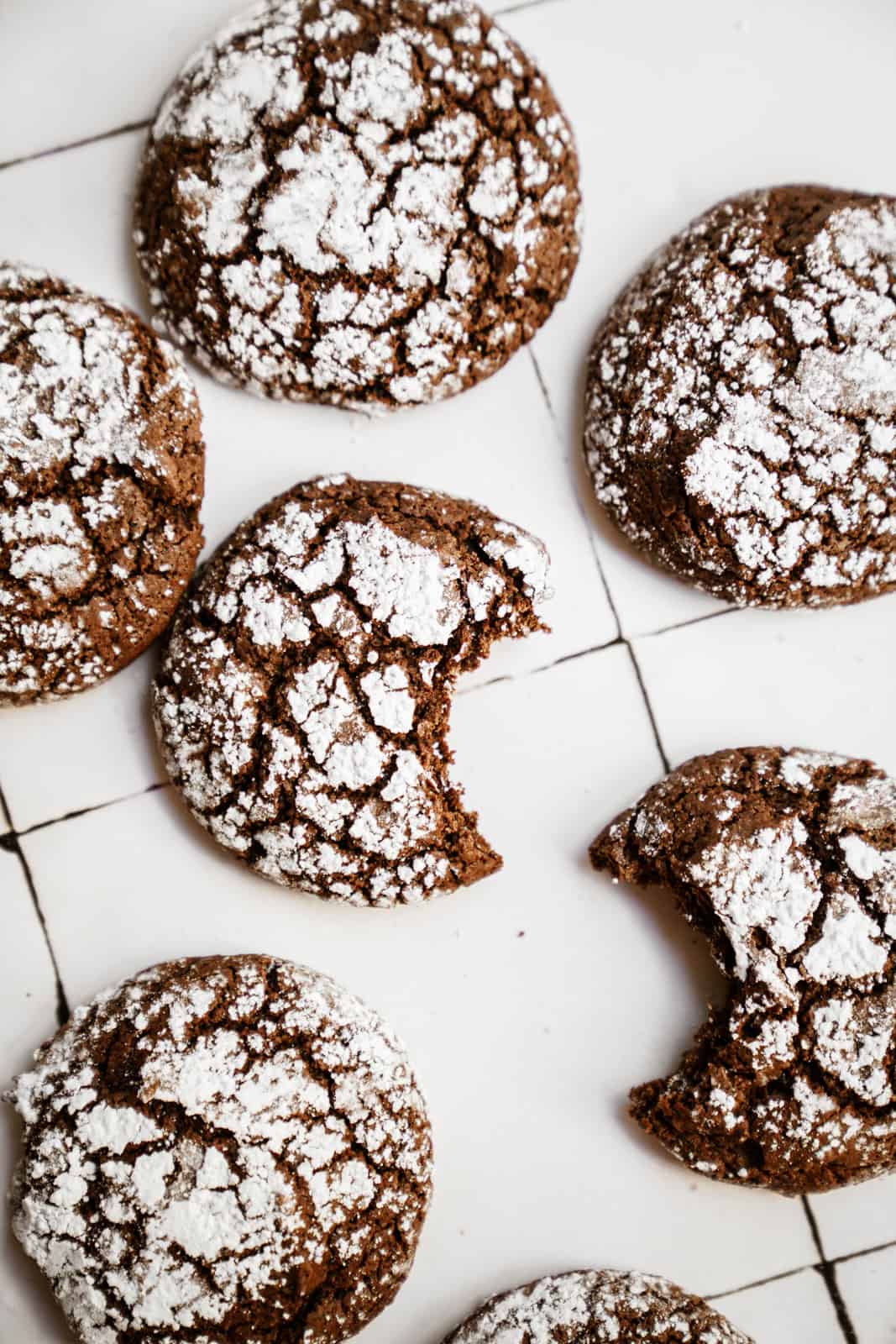 Cookies from my Chocolate Crinkle Cookie Recipe scattered on white countertop.