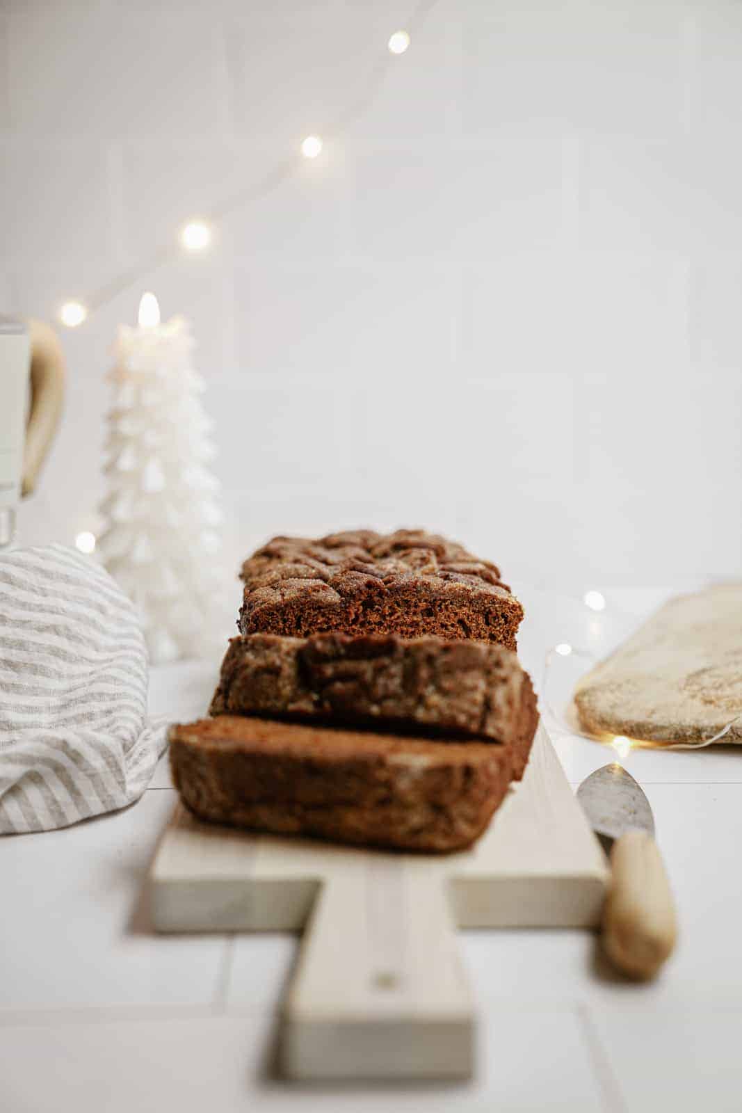 Vegan gingerbread loaf sliced on cutting board.