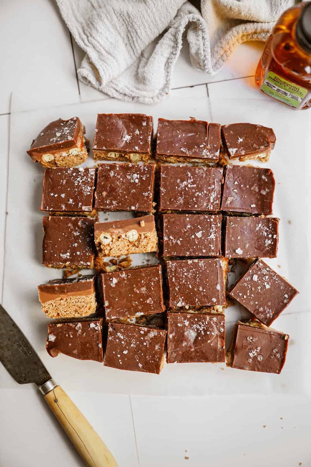 Cut Caramel Pretzel Bars on countertop next to a knife and teatowel.