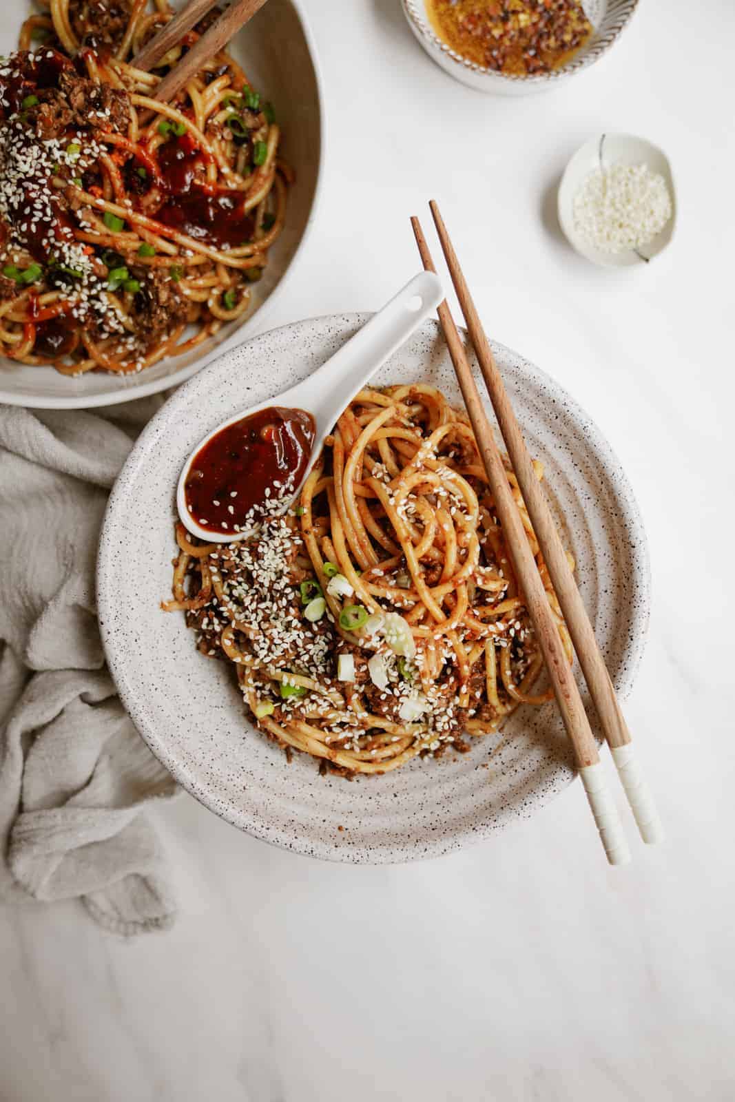 Vegan dan dan noodles in a white bowl with chopsticks.