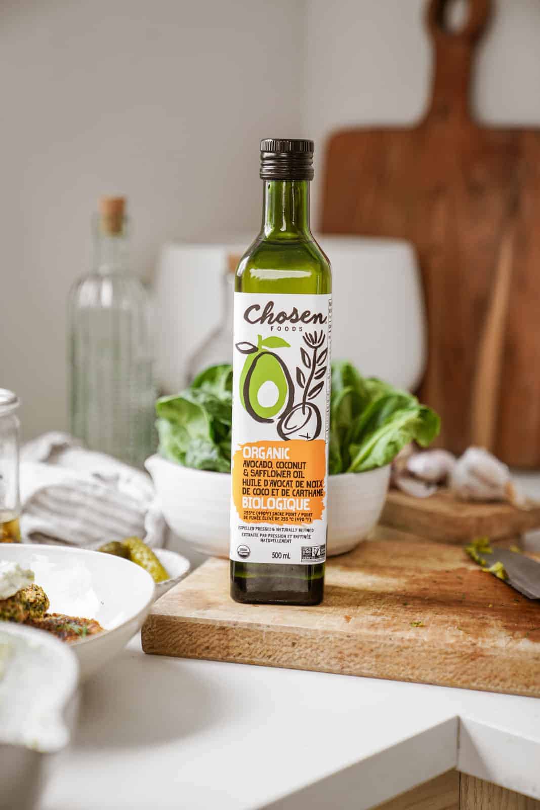 Chosen Foods avocado oil sitting on cutting board on counter.