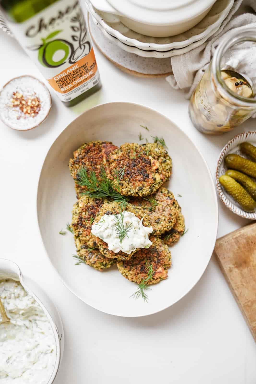 Quinoa and Spinach Patties on serving dish on countertop surrounded by ingredients.