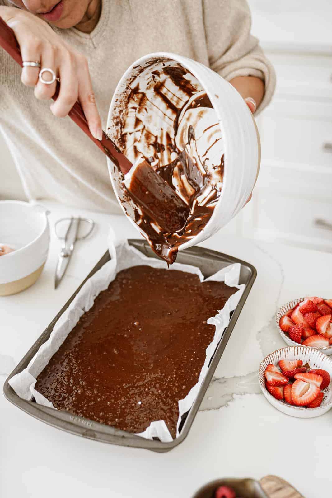 Maria pouring cake batter into pan for sheet cake.