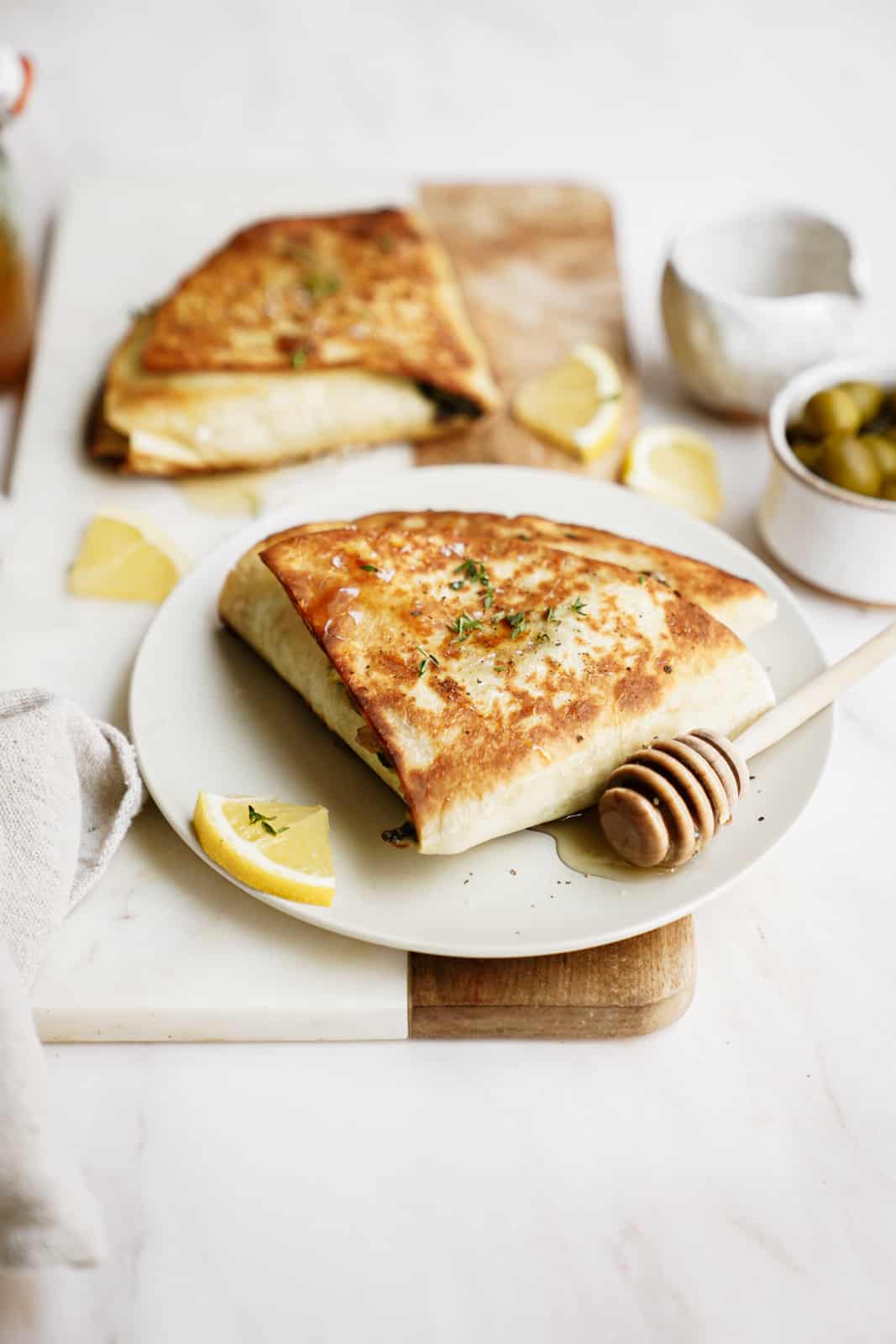 Trendy spinach wrap made greek-style cut into triangles on white plate