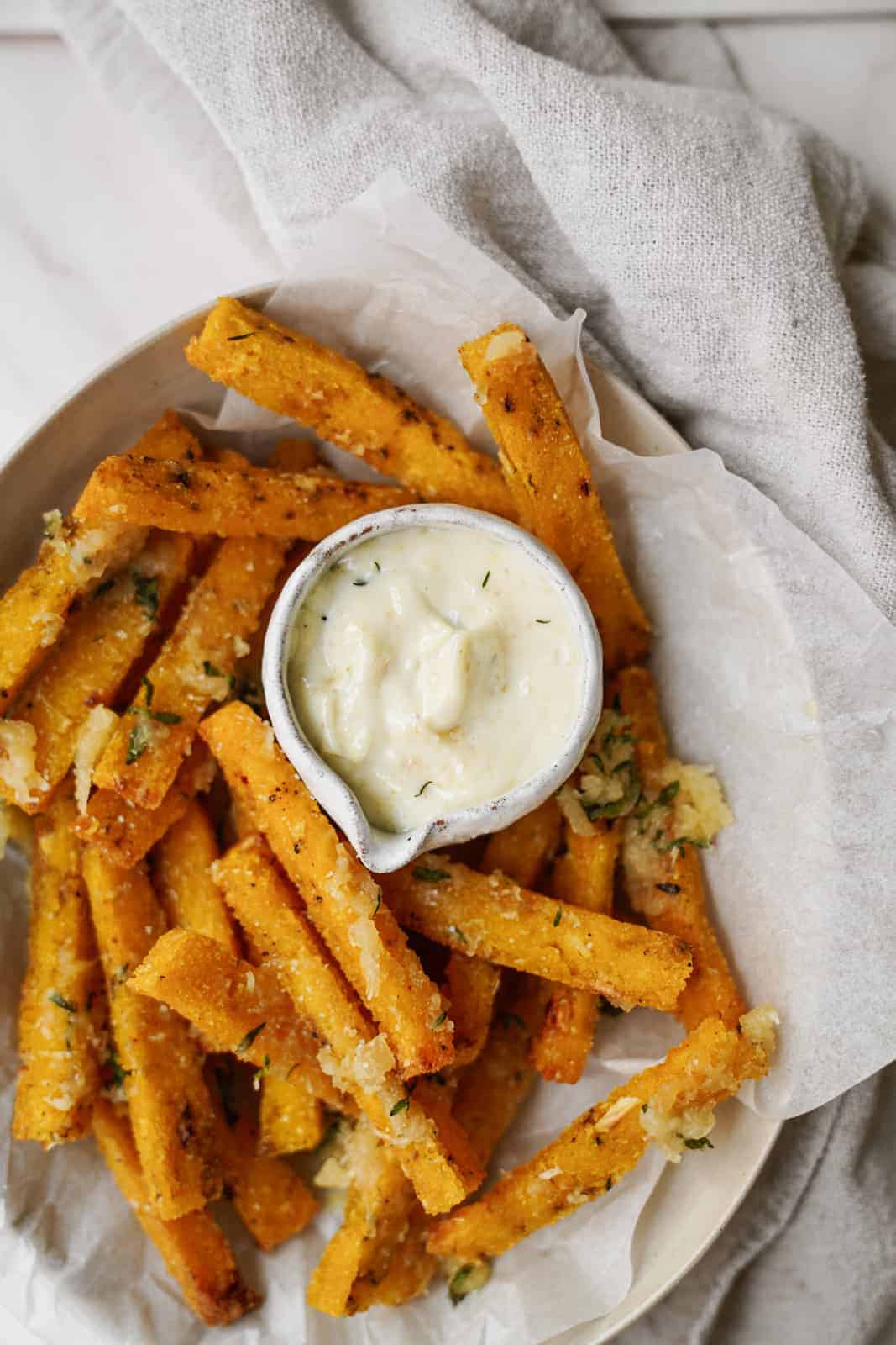 Bowl of vegan polenta fries with a side of aioli.