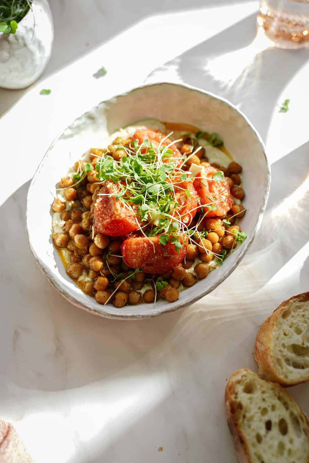 oven-roasted chickpeas in a white bowl with slices of bread next to it