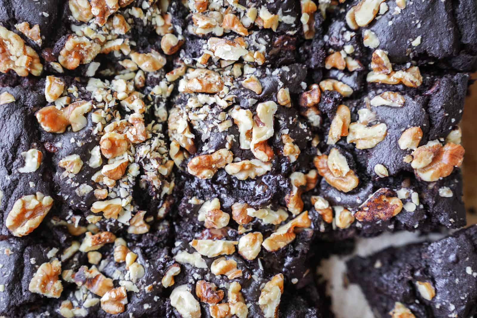 Close-up of vegan fudge brownies on a cutting board with a piece cut out