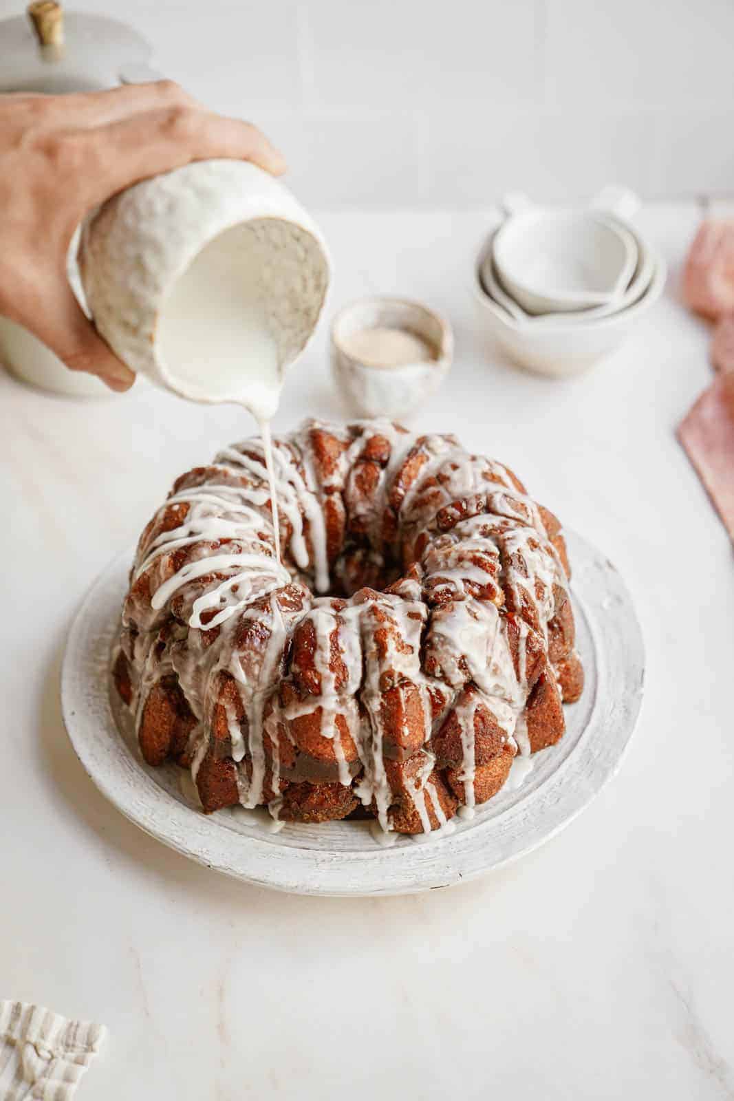 Vegan monkey bread on plate being drizzled with icing