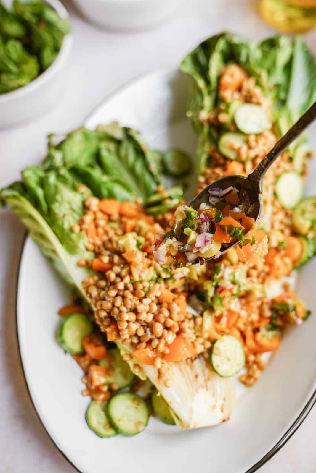 grilled romaine salad with lentils and olive salsa being sprinkled on top