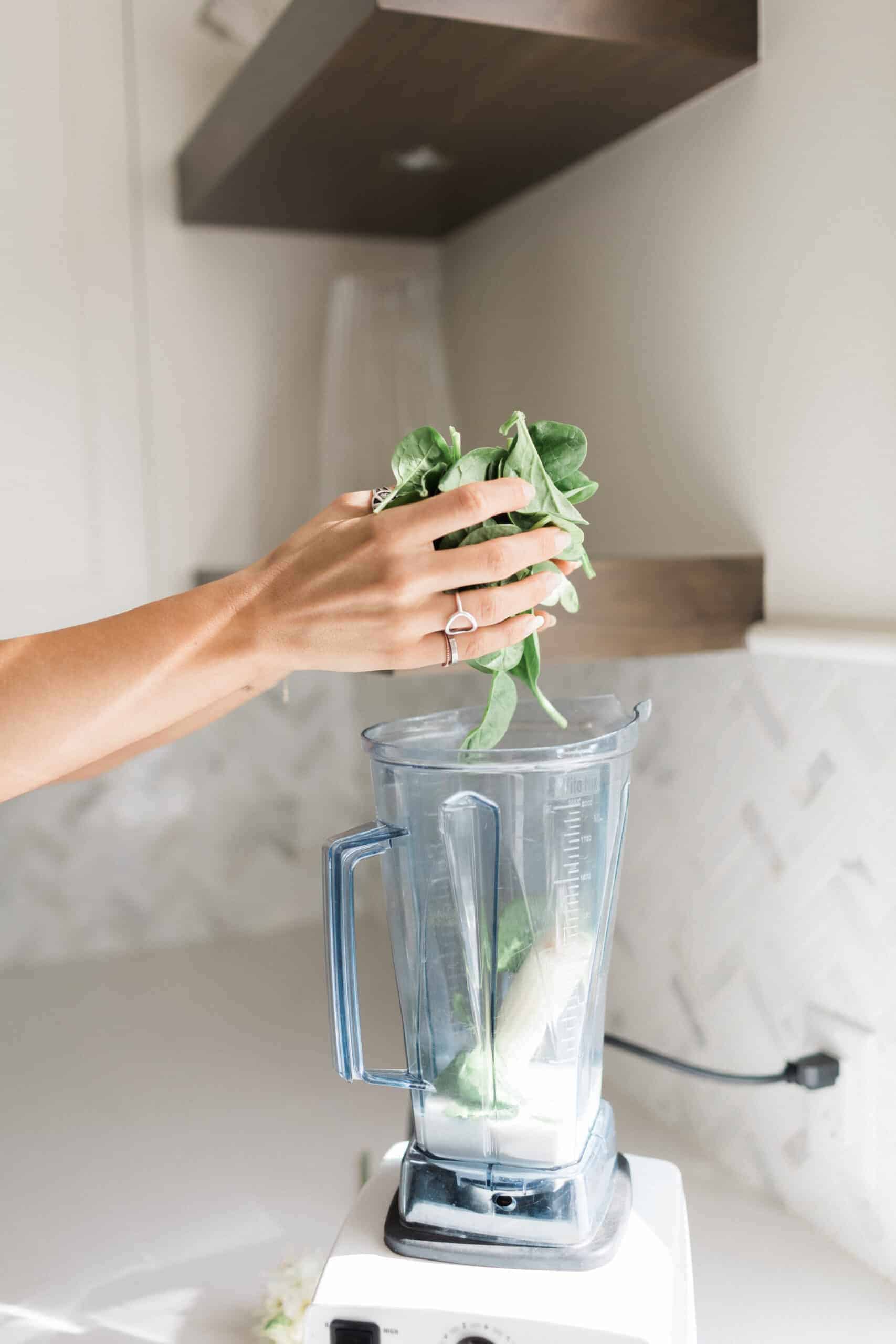 Spinach being added to blender for banana berry smoothie