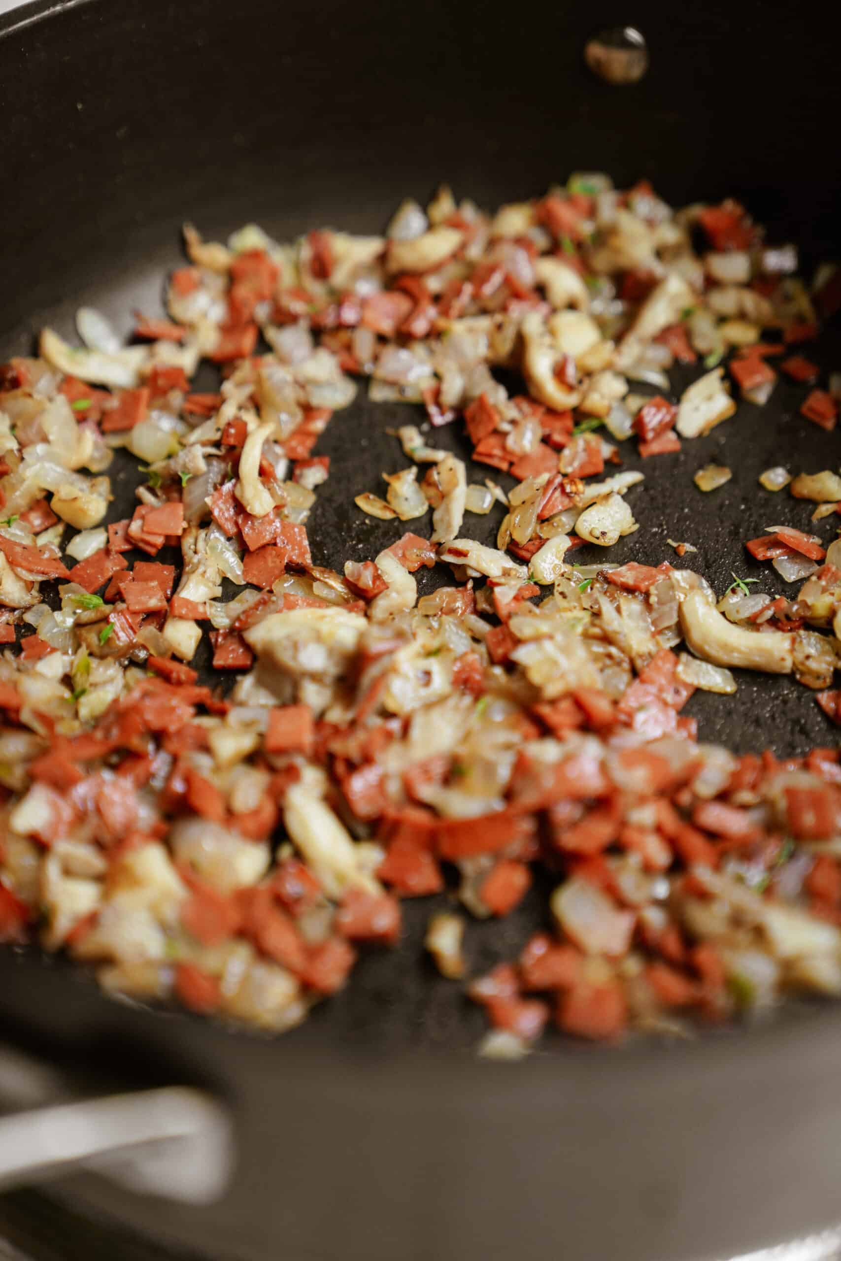 Bacon and other ingredients frying in a pan