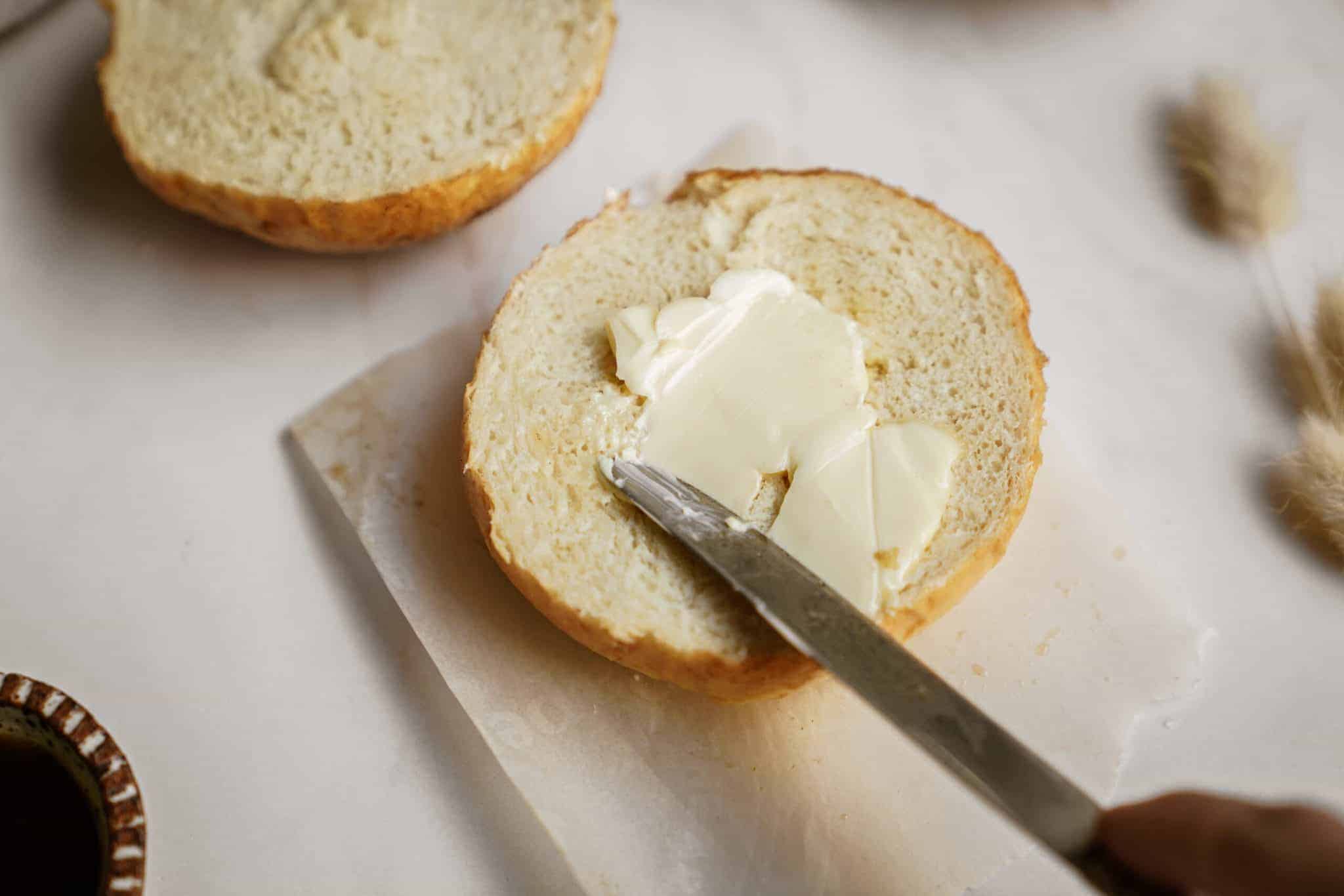 Butter being spread on dinner roll recipe