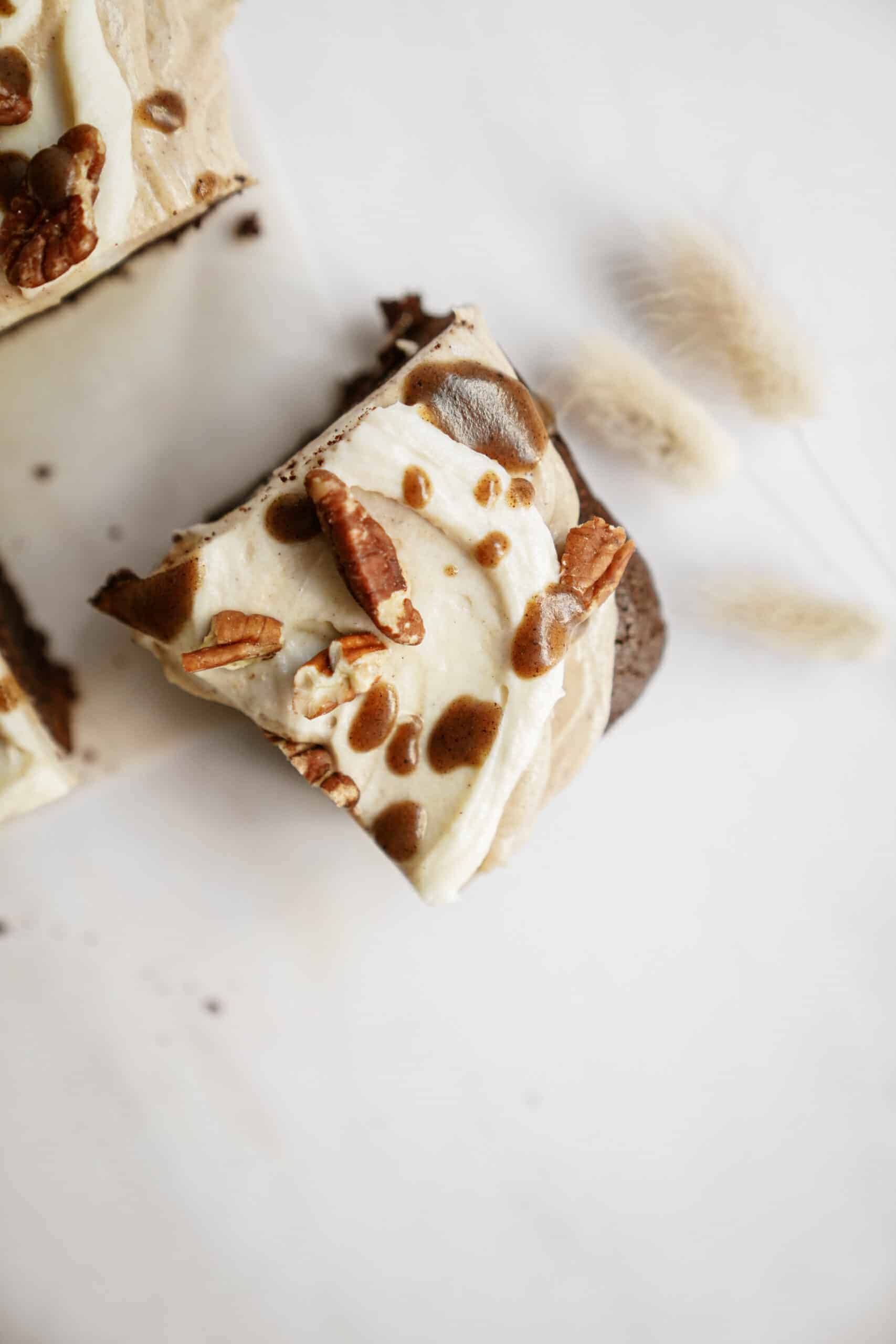 Slice of fudge brownies with pecans and icing on top