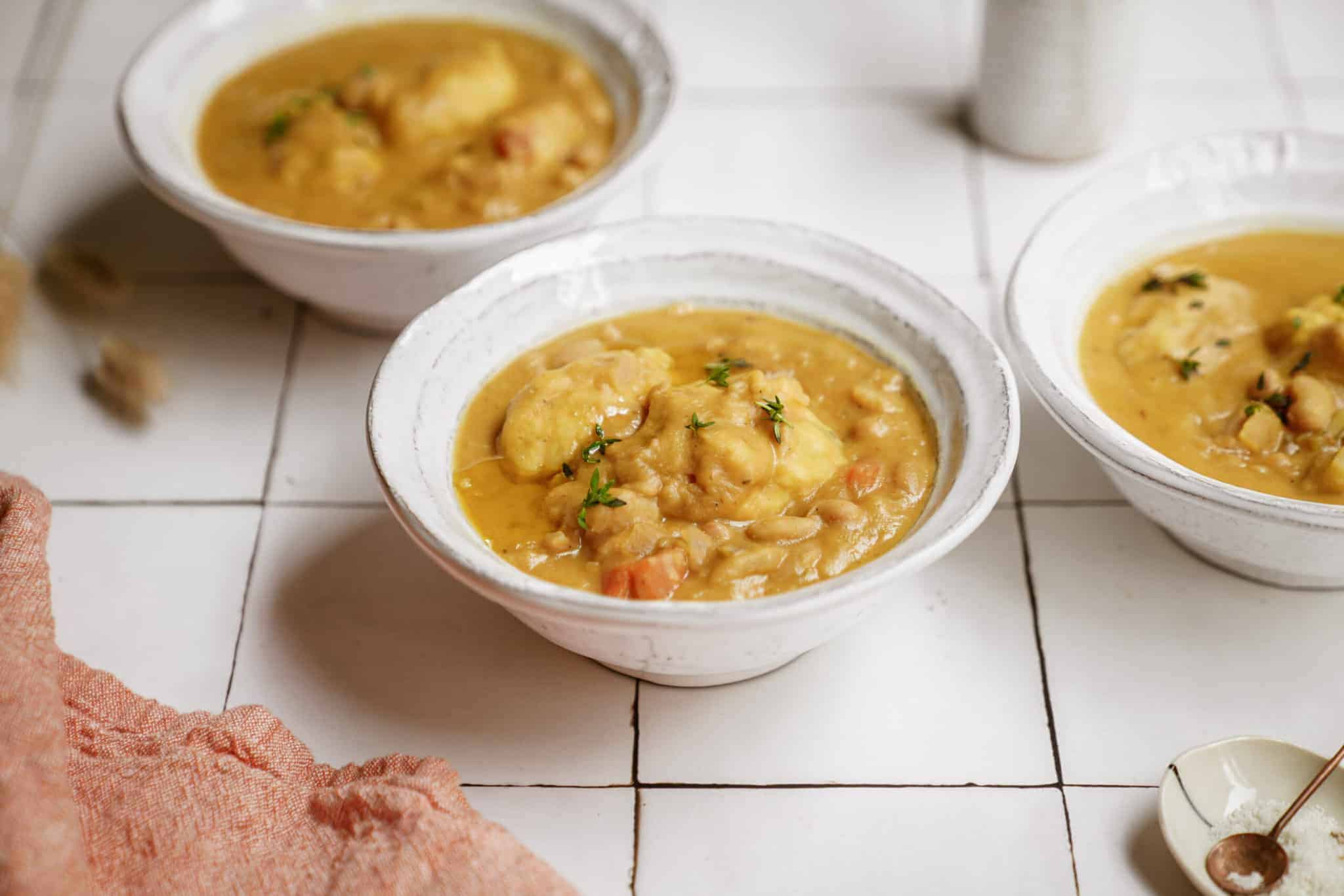 White bean soup with soup dumplings in bowls on countertop 